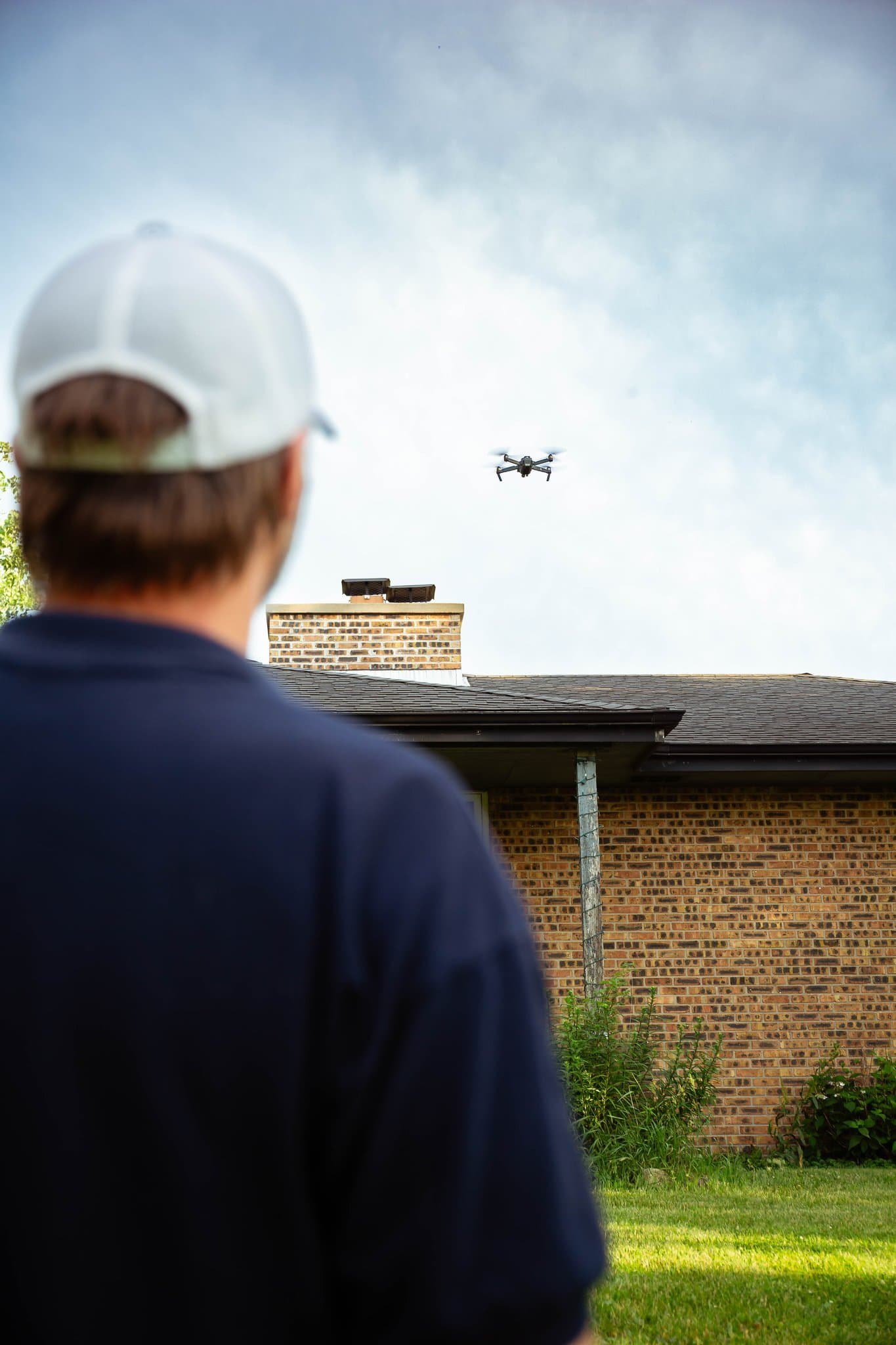 A drone hovering over a home’s roof and chimney during an aerial inspection