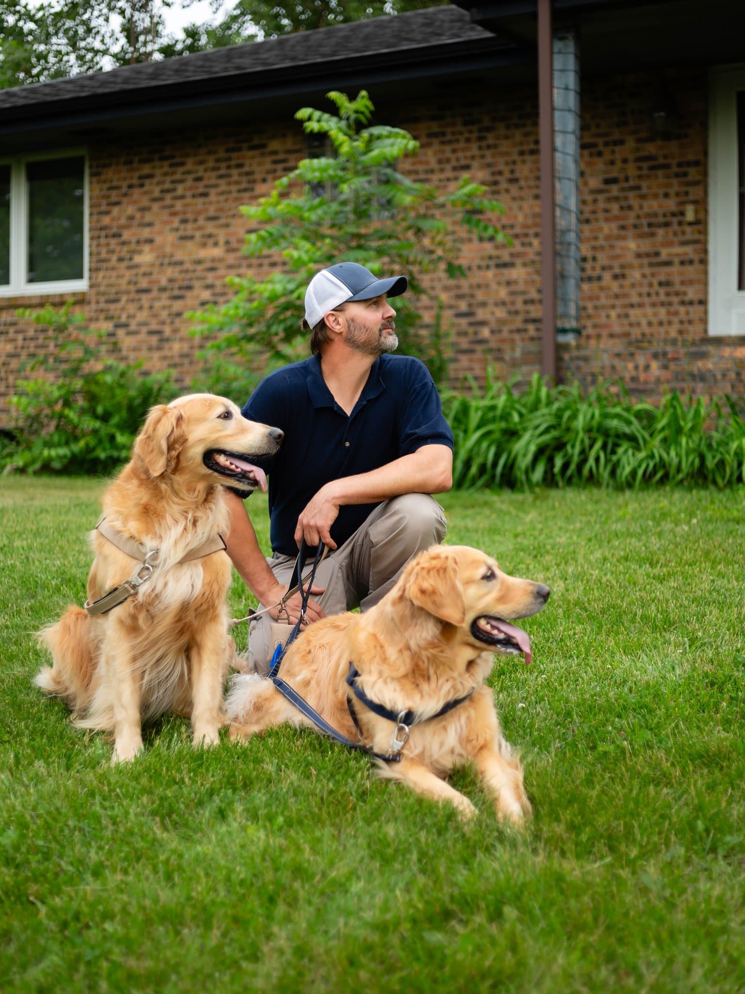 Mike Lacheta with his two golden retrievers in front of a brick home